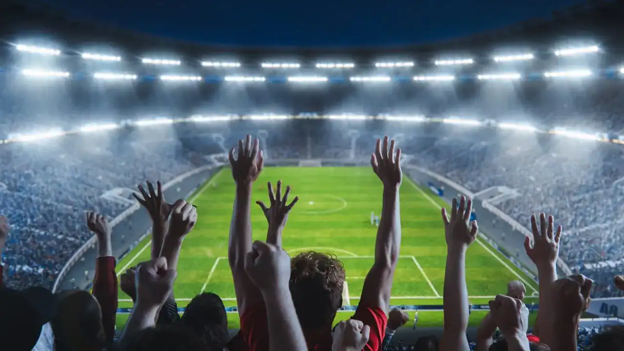 Excited fans cheer in a brightly lit stadium during a soccer match, highlighting AI's role in sports per Capgemini study.